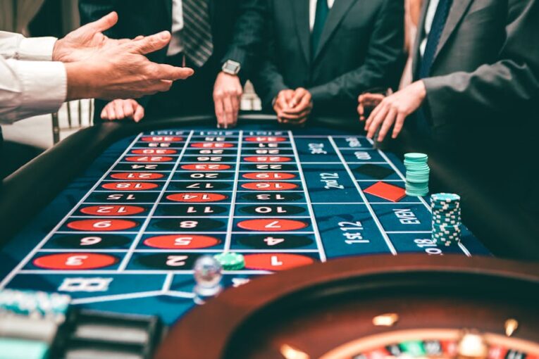 Group of people playing roulette, placing bets in a casino setting.